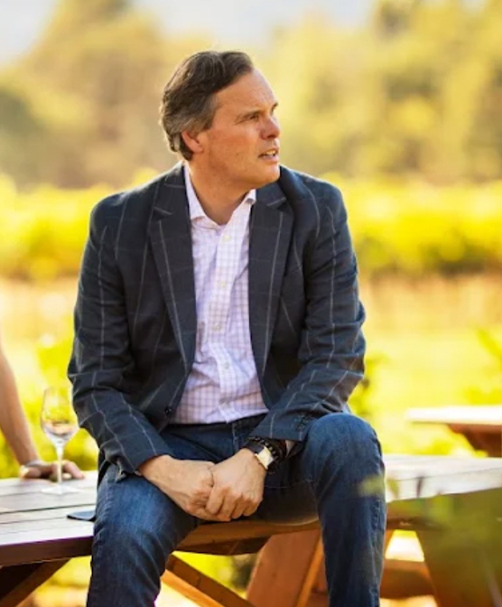 Maurice sitting on a picnic table with glass of wine